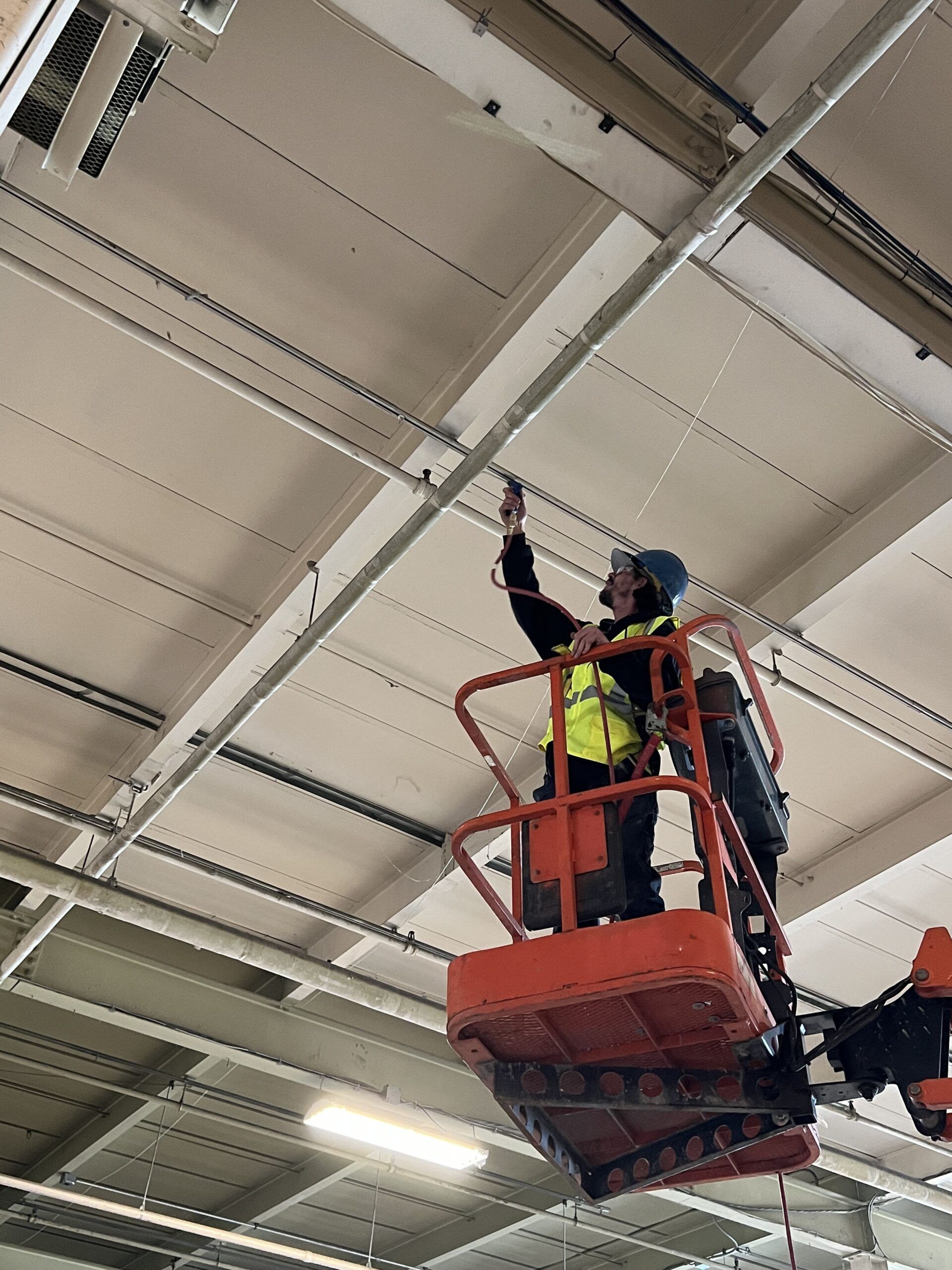 A Man Is Standing on A Lift Working on The Ceiling of A Building | S. Glens Falls, NY | Performance Industrial