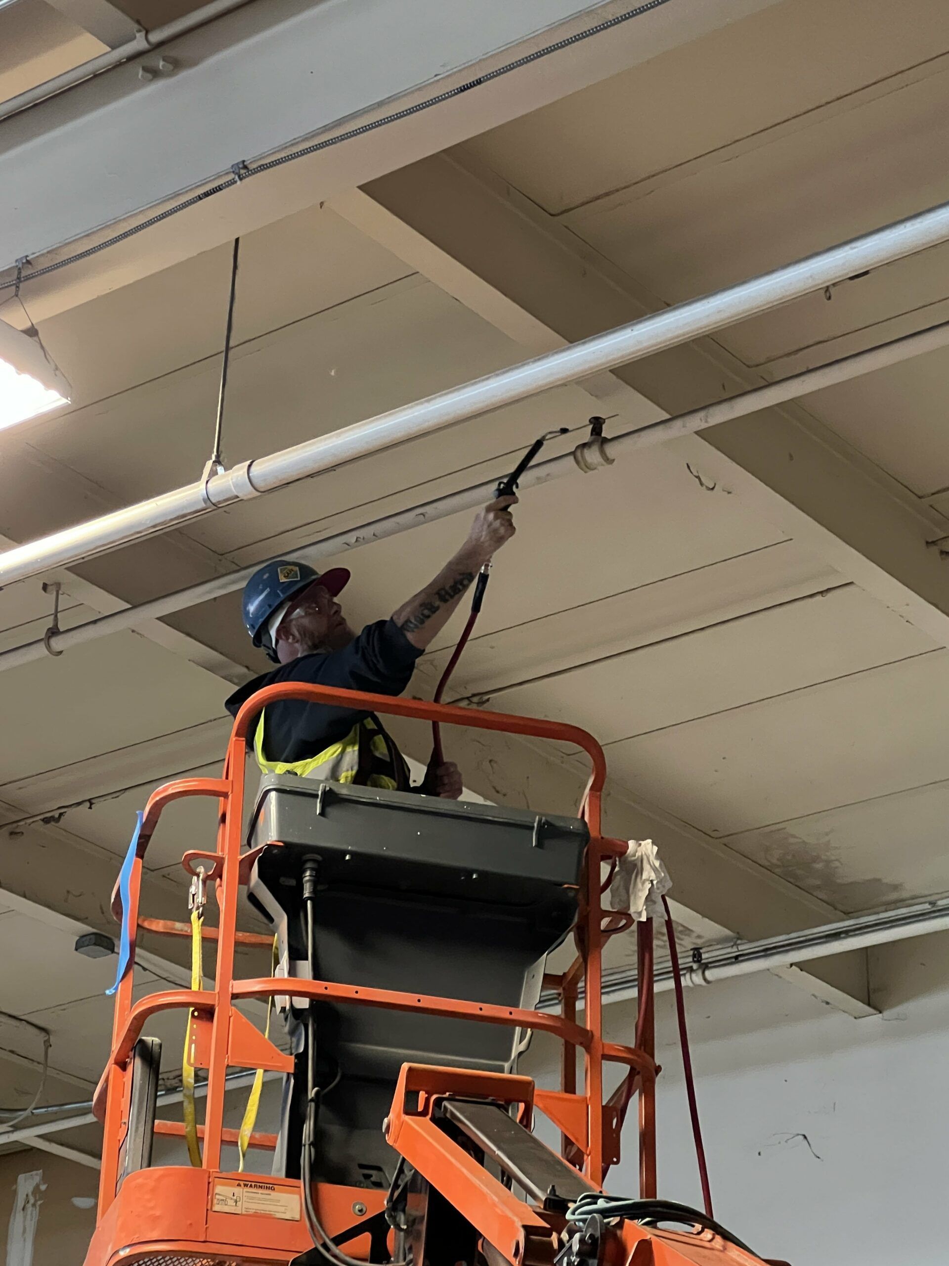 A Man Is Cleaning the Ceiling of A Building on A Lift | S. Glens Falls, NY | Performance Industrial