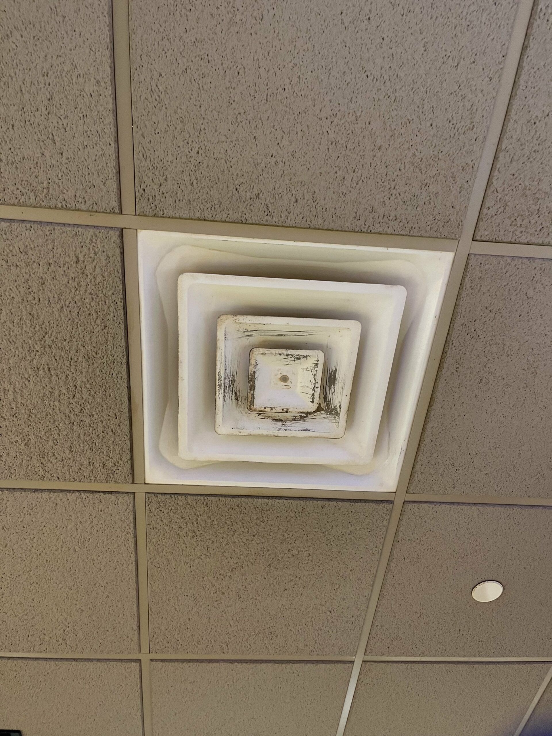 A dirty air vent on the ceiling of a building