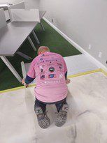 A Man In A Pink Shirt Is Kneeling On The Floor