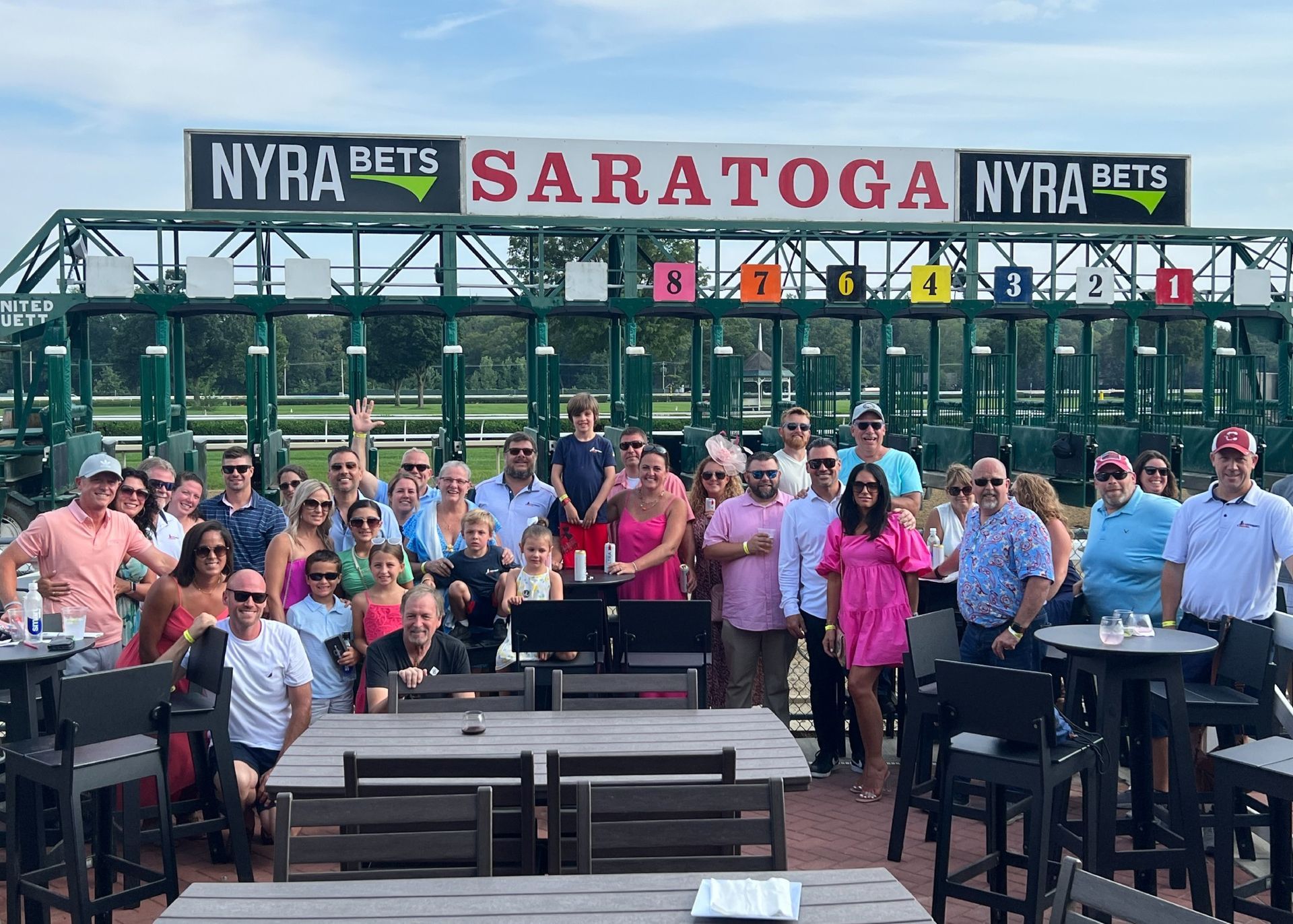 A group of people are posing for a picture in front of a sign that says saratoga nyra bets.