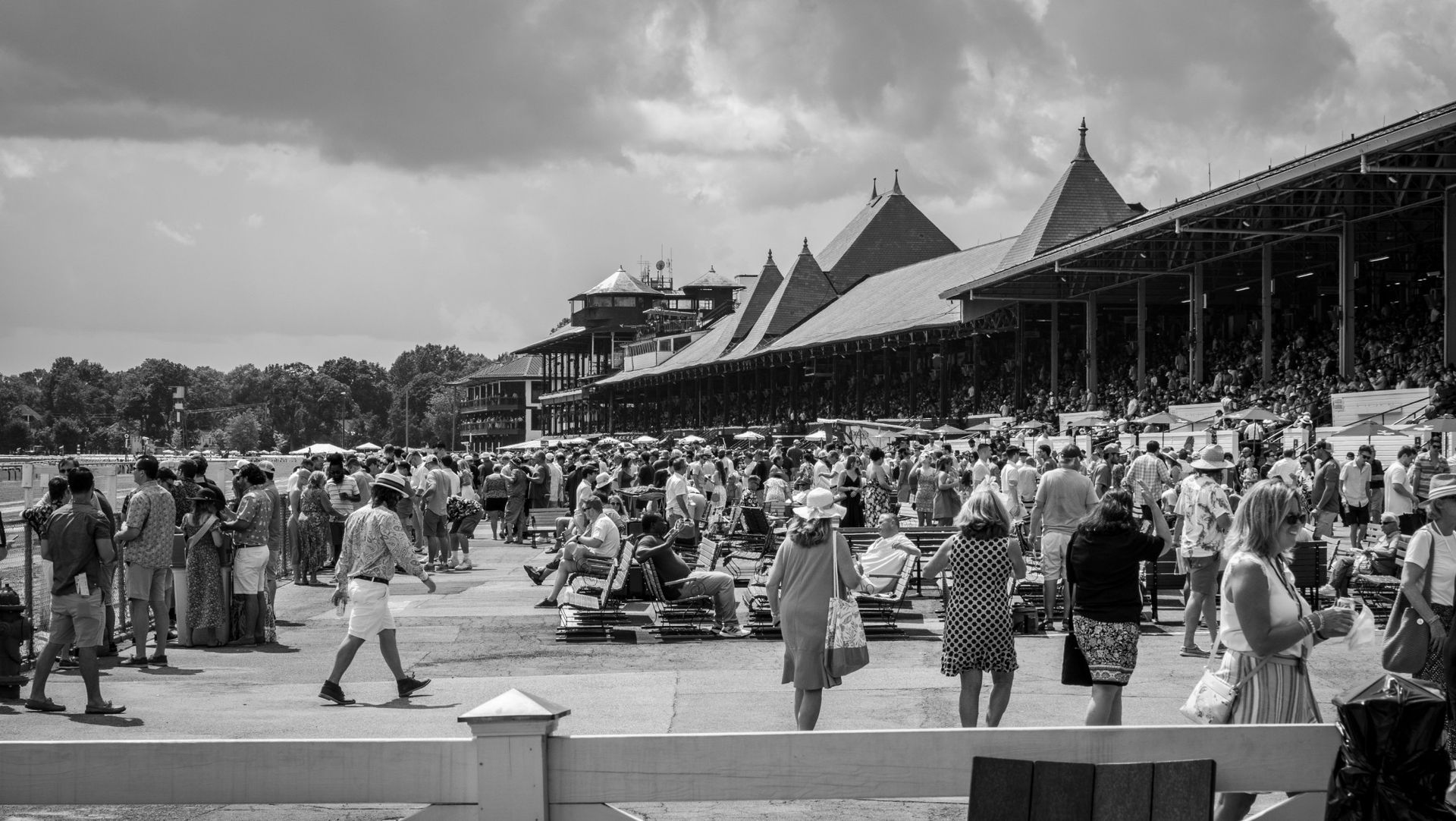 A black and white photo of a crowd of people at a race track