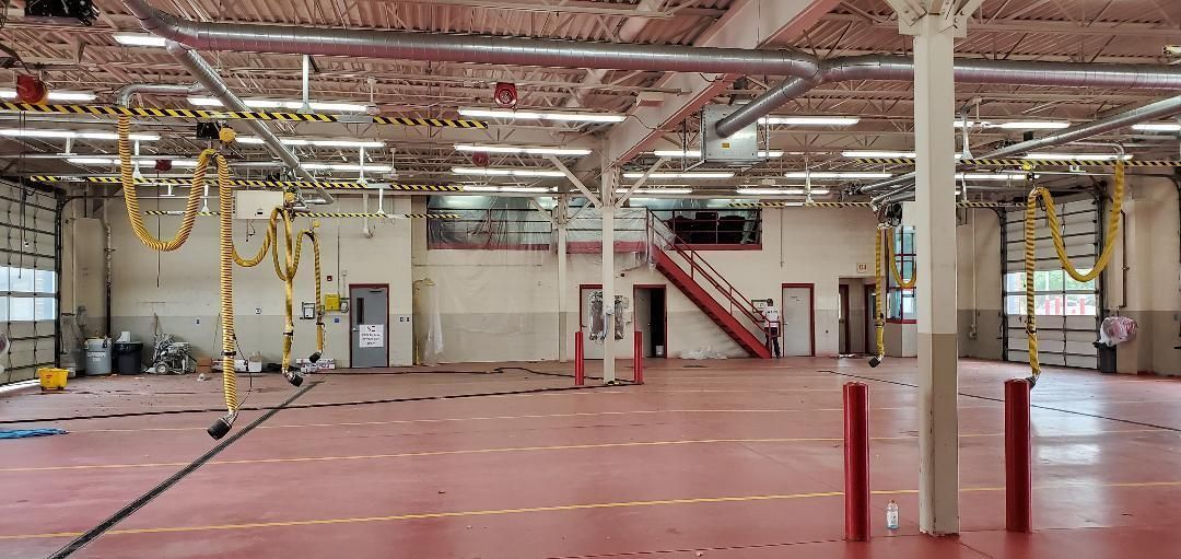 A large empty warehouse with a red floor and a staircase.