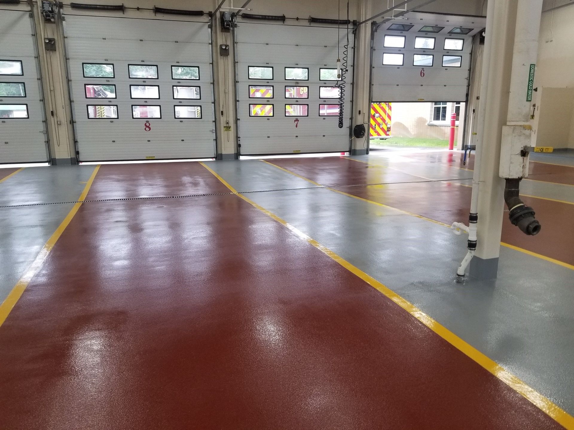 An empty garage with a red floor and yellow lines