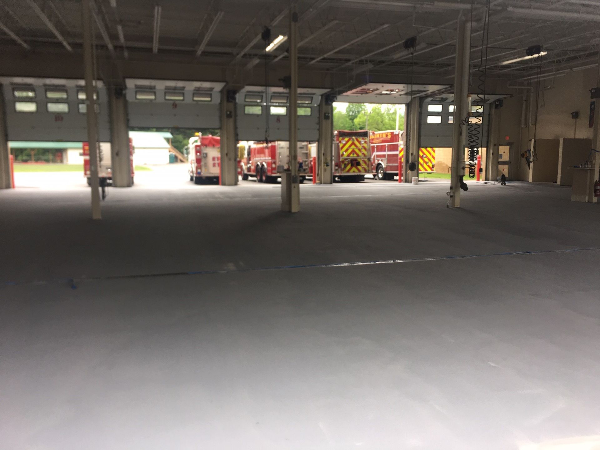 A row of fire trucks are parked in a garage.