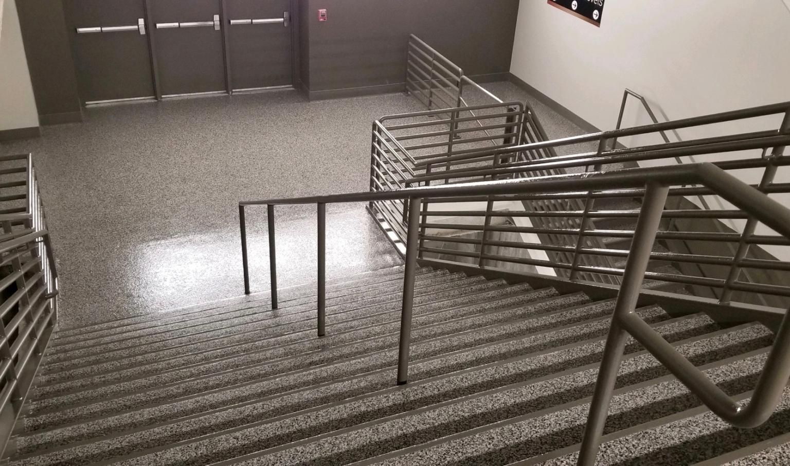 A staircase with a metal railing and a ramp in a building.