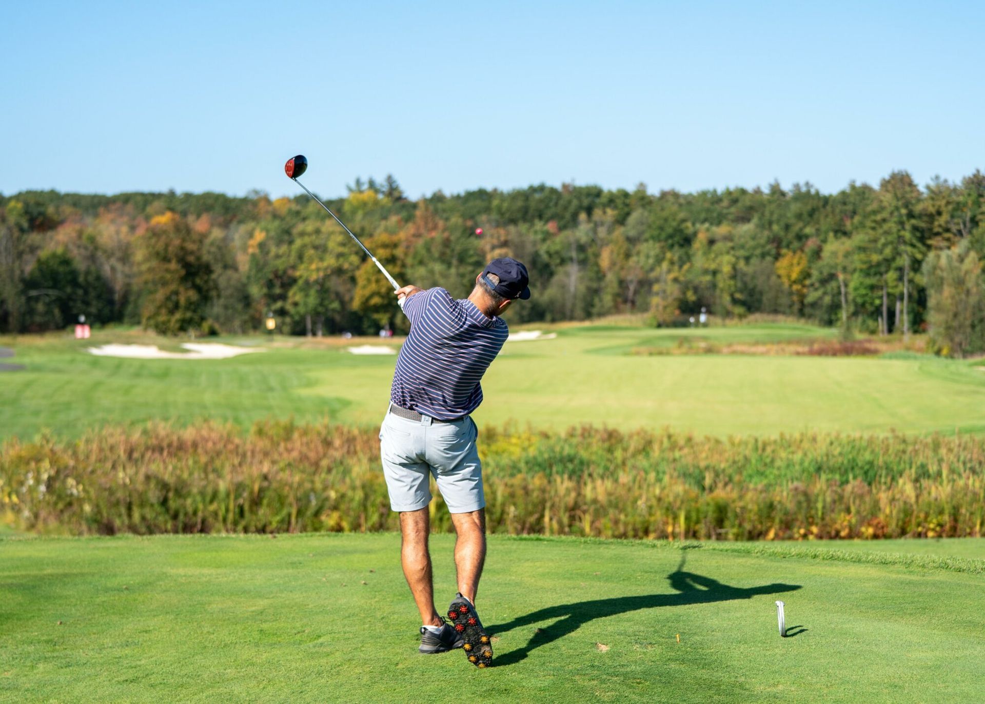 A man is swinging a golf club at a golf ball on a golf course.