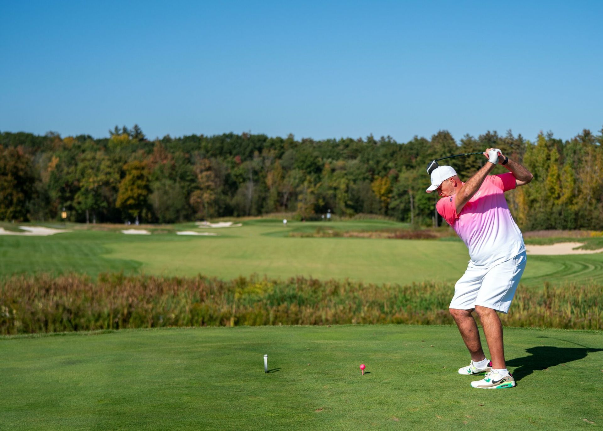 A man is swinging a golf club at a golf ball on a golf course.