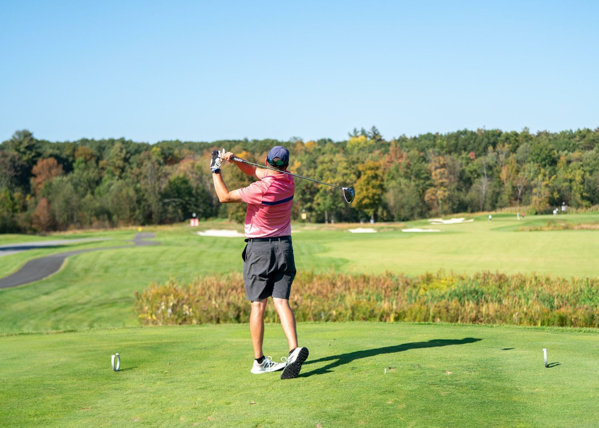 A man is swinging a golf club on a golf course.