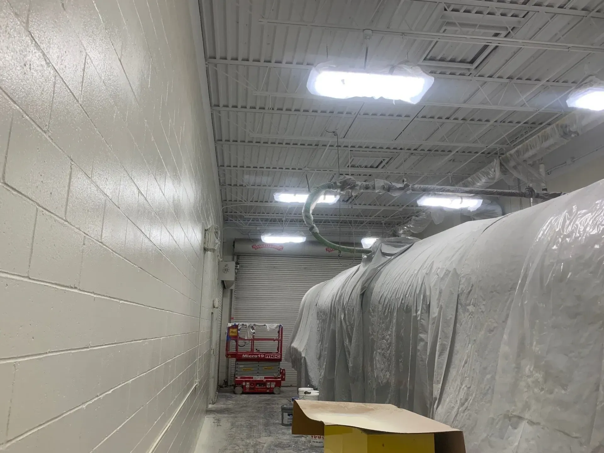 A hallway in a building with white walls and ceilings covered in plastic.