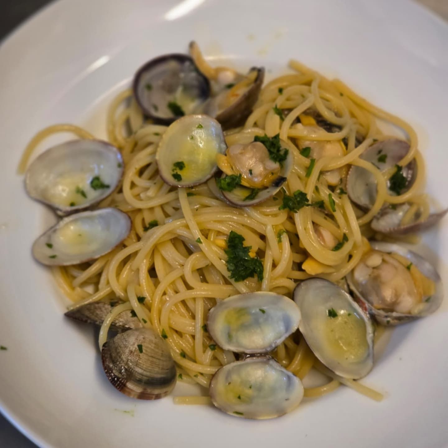 Due carciofi e verdure su un piatto bianco, supporto in legno con menu sullo sfondo.