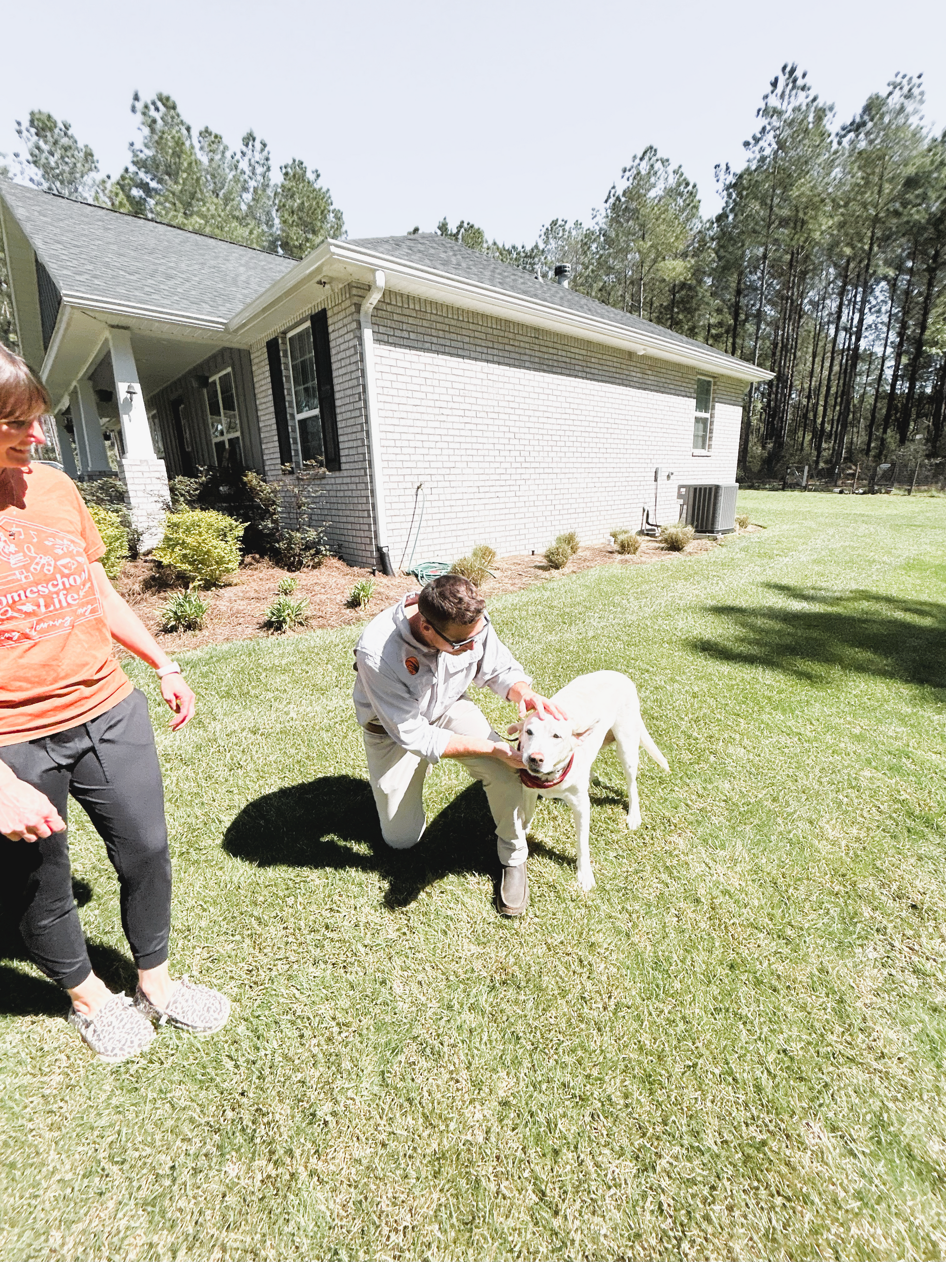 Two people playing with a dog in front of a house