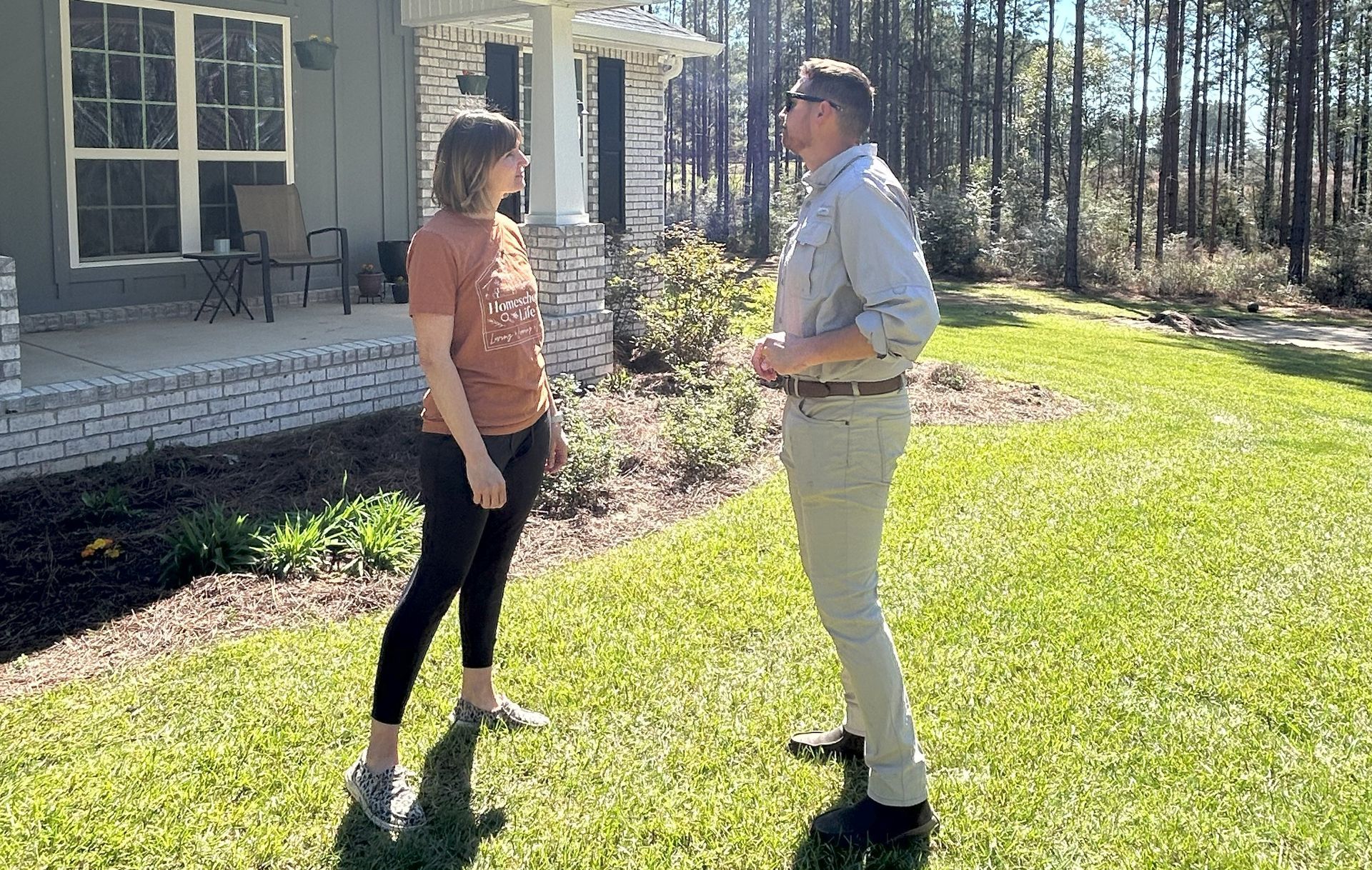 A man and a woman are standing in front of a house talking to each other.