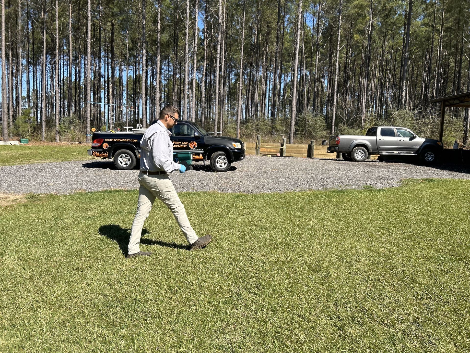 A man is walking in a grassy field next to a truck.