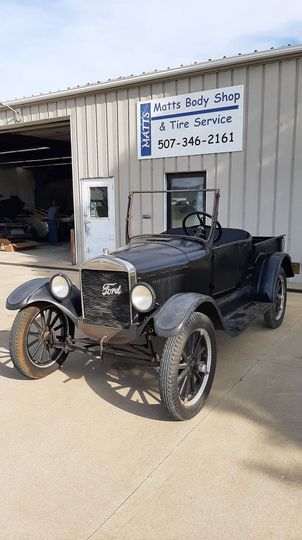An old car is parked in front of a building.