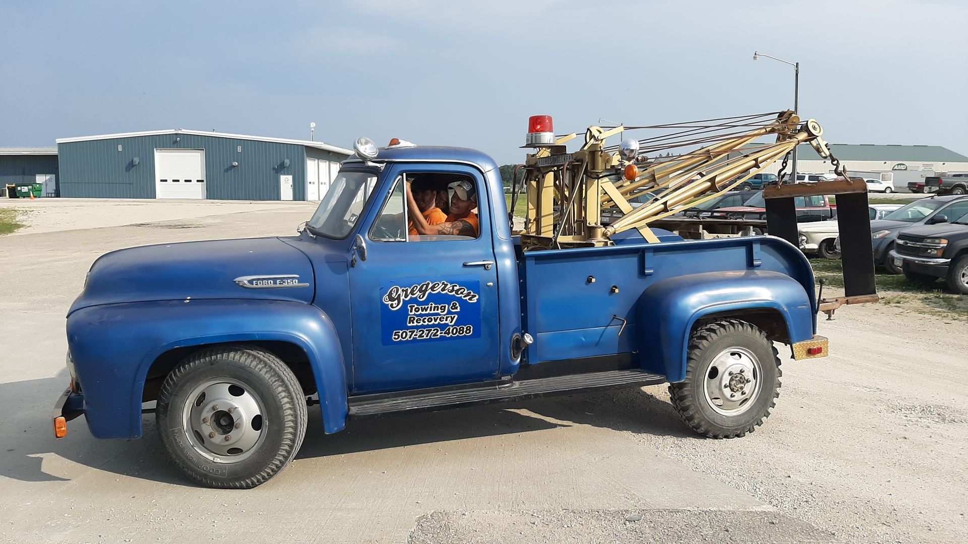 A blue tow truck is parked in a gravel lot