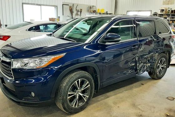 A blue toyota highlander is parked in a garage.