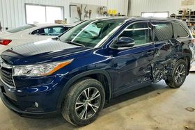 A blue toyota highlander is parked in a garage.