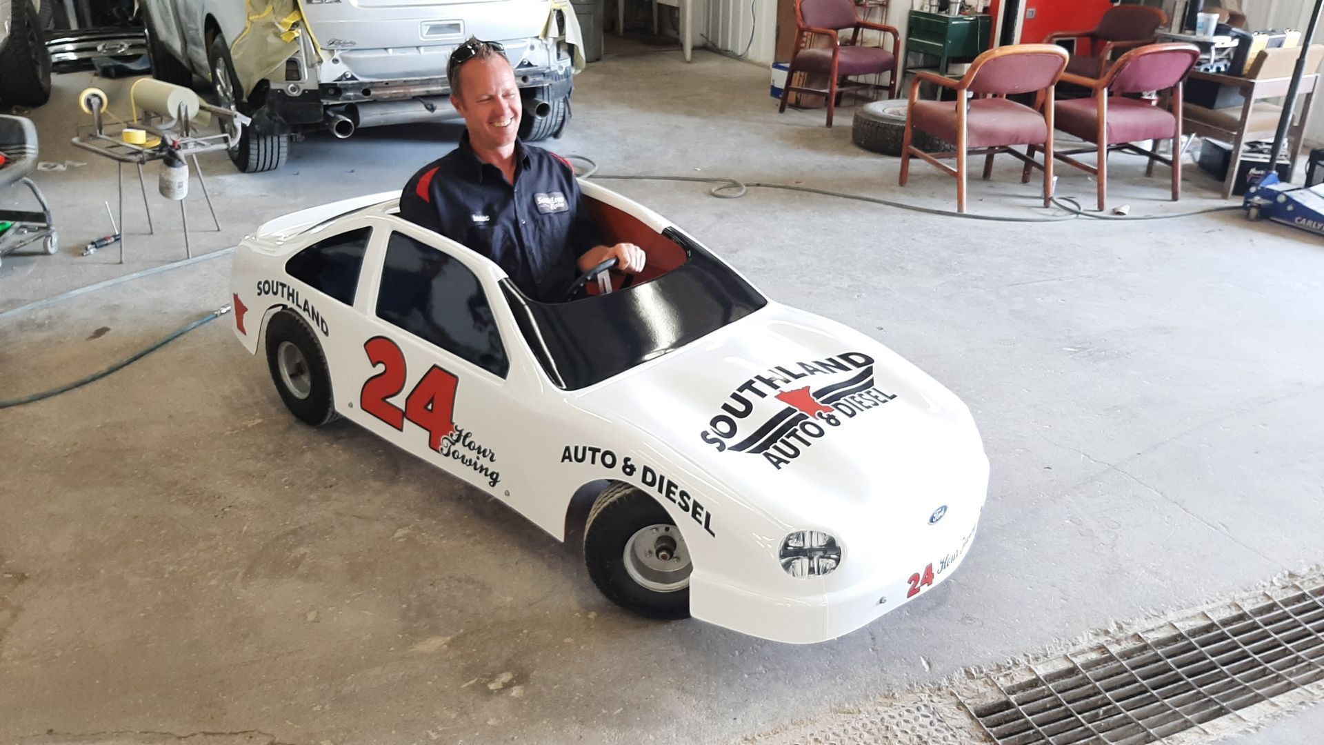 A man is driving a small race car with the number 24 on it