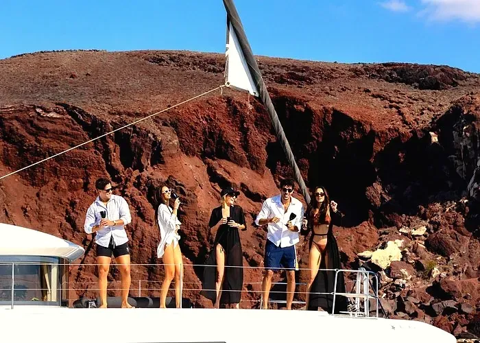 Guests enjoying a private Santorini catamaran cruise near Red Beach cliffs during a combo tour from a cruise ship