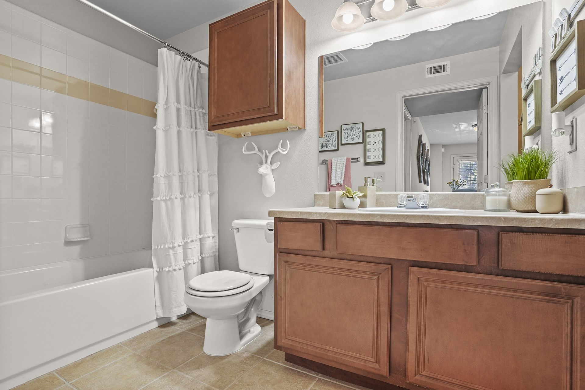 Bathroom with wooden vanity, toilet, and shower-tub in apartment.