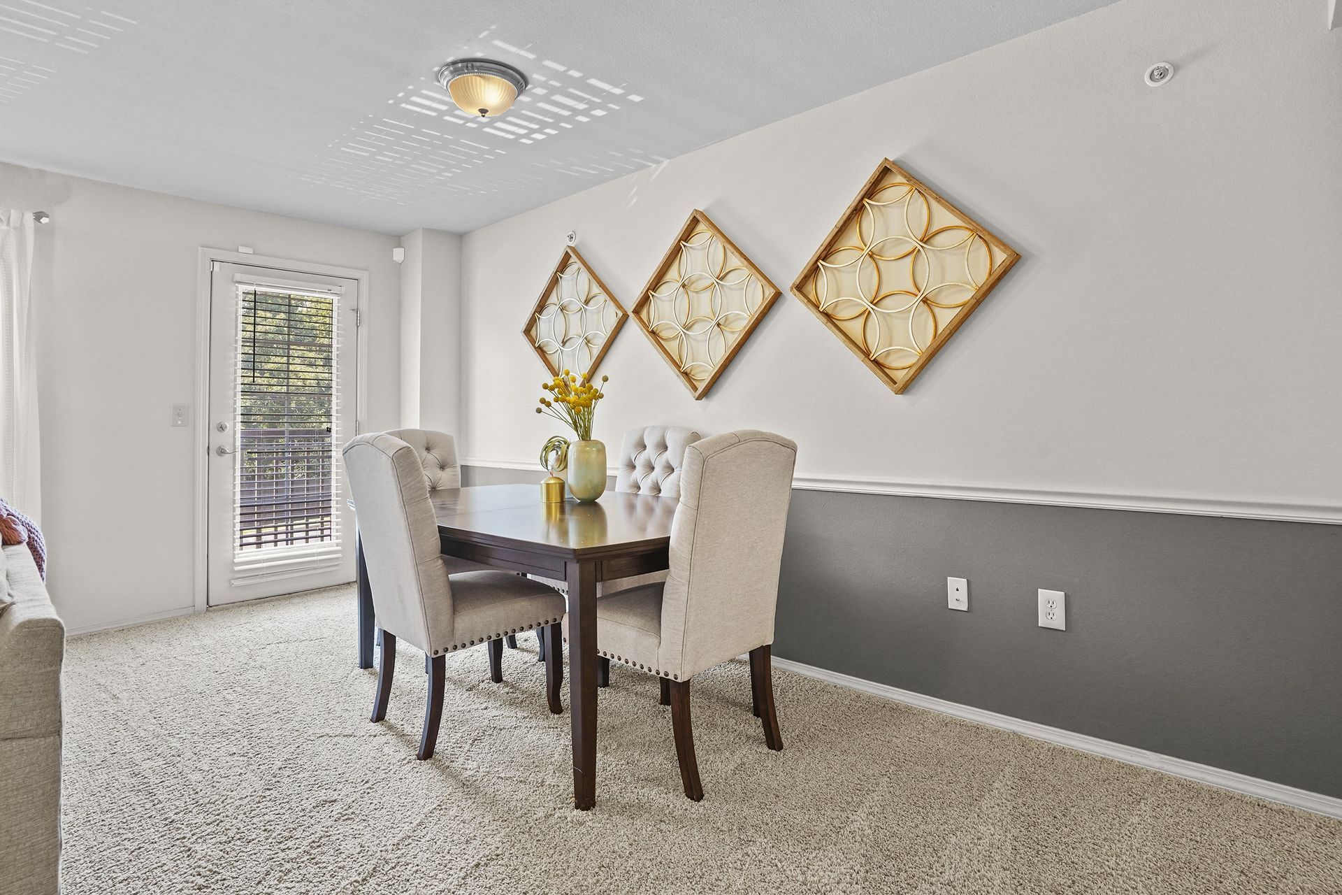 Dining room with a table and chairs, decorated with wall art and a door to the outside.