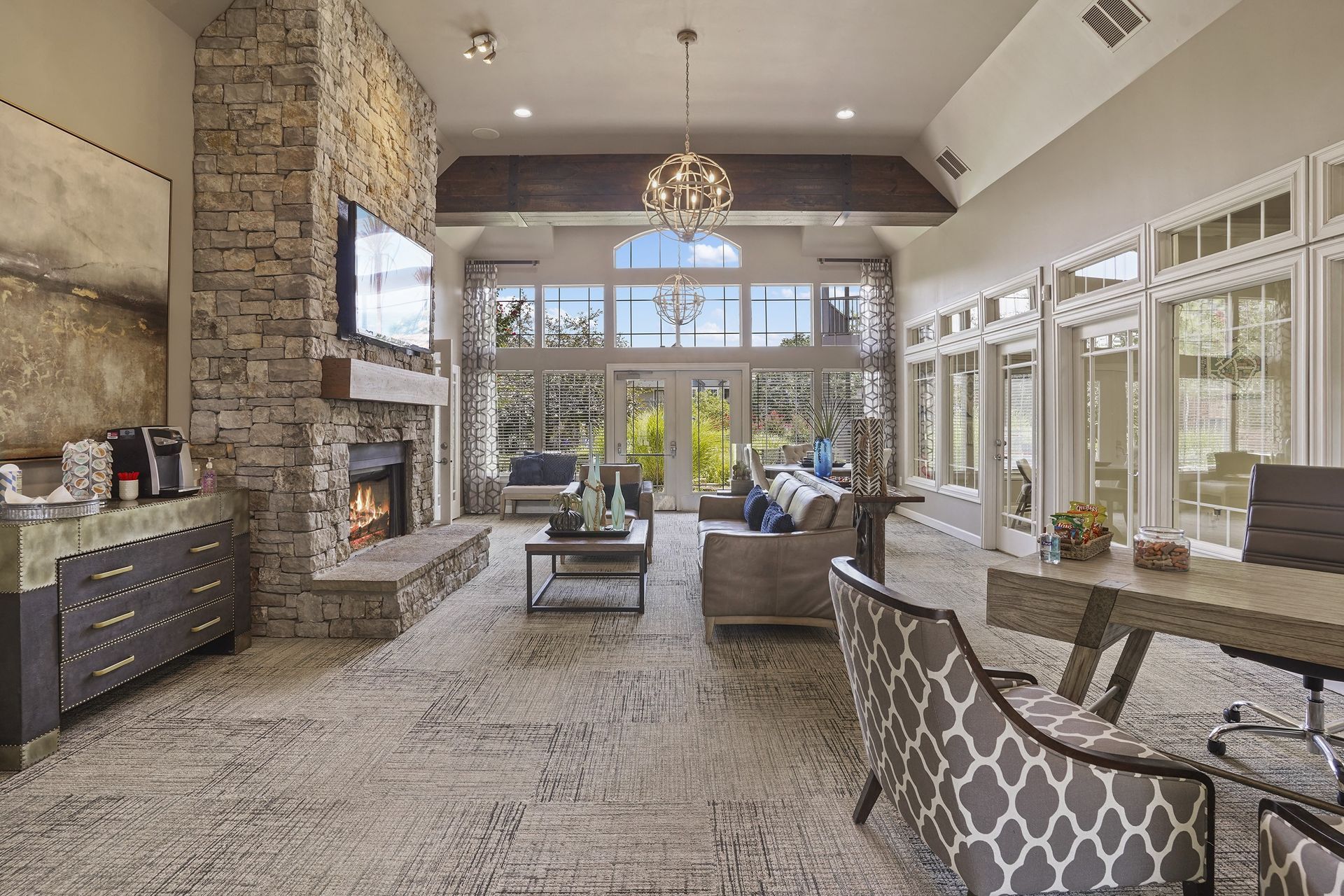 Lobby with stone fireplace, sofas, coffee table, desk, and large windows overlooking a courtyard.