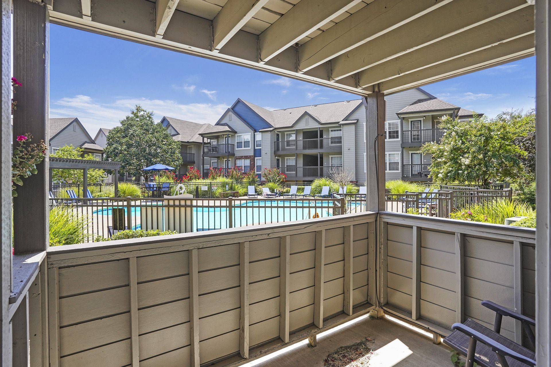 Balcony view overlooking a communal pool area with lounge chairs and surrounding apartment buildings.