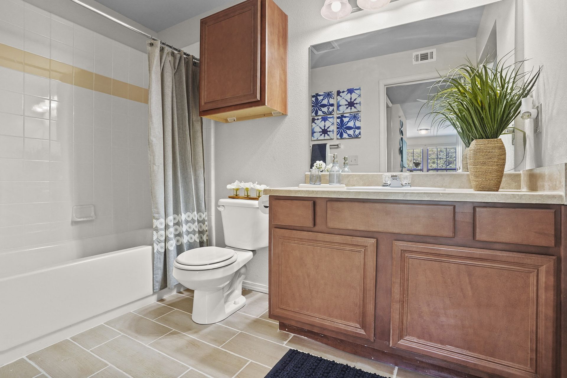 Bathroom with bathtub/shower, toilet, and wooden vanity.