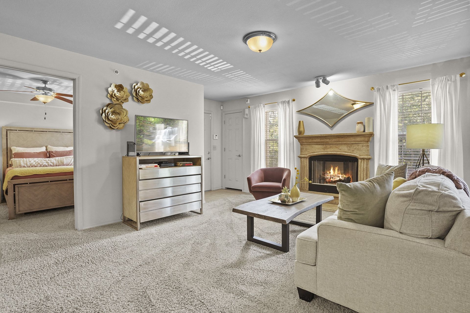 Living room in an apartment with a fireplace, sofa, coffee table, TV, and doorway to a bedroom.