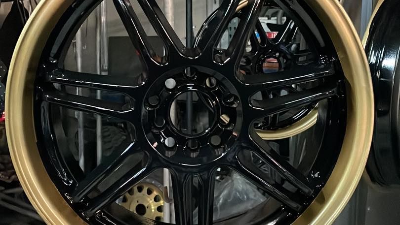 Un primer plano de una rueda negra con borde dorado.