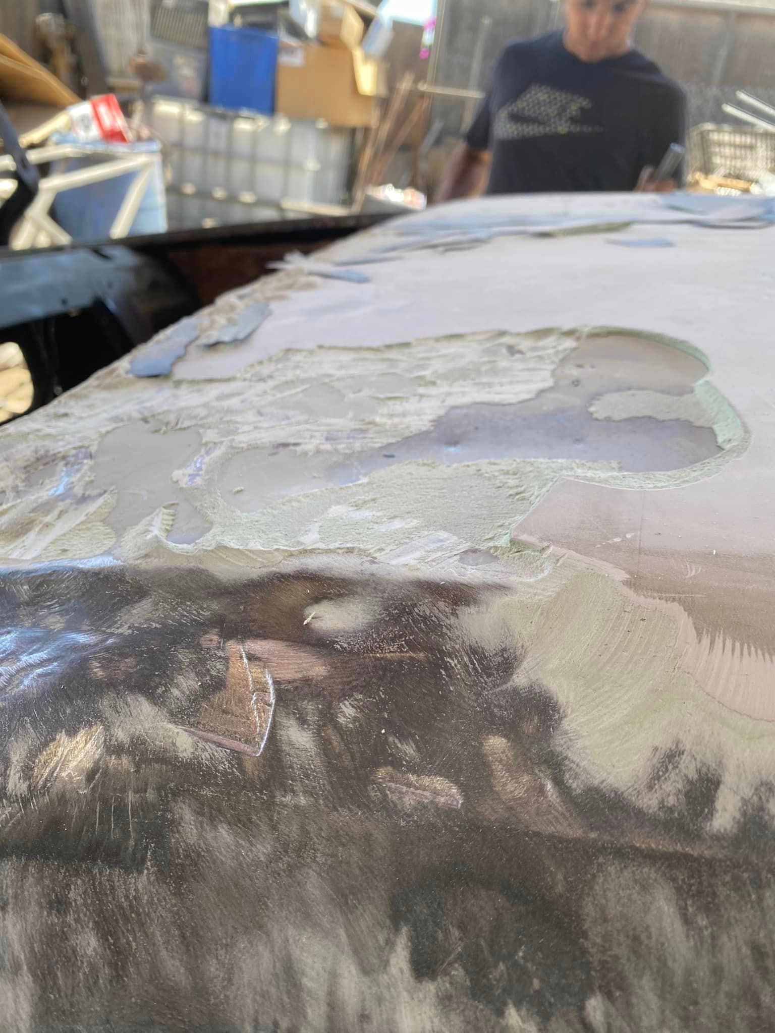 Un primer plano de una pieza de metal con un hombre al fondo.