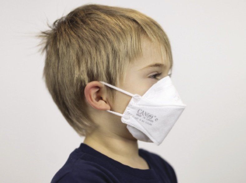 A young boy wearing a white mask with a canon logo on it