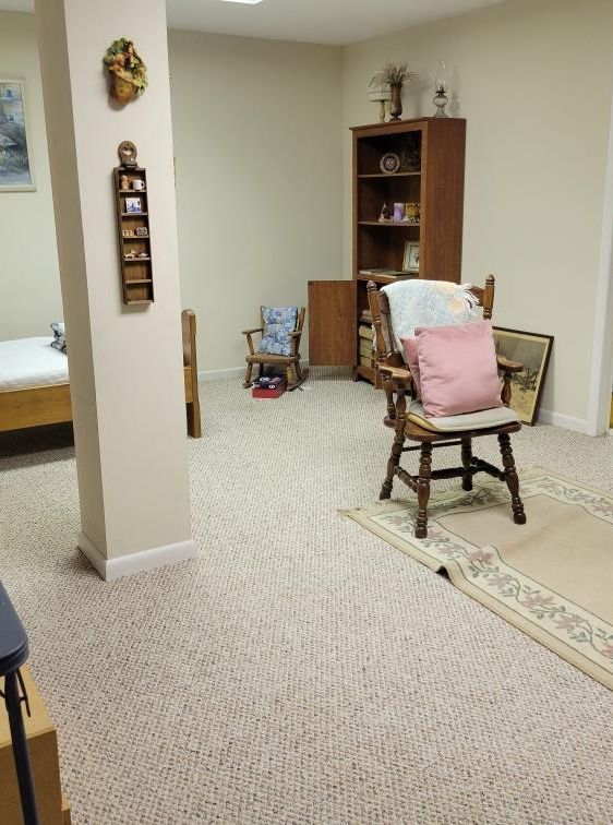 Cozy room with a column, bookshelf, and chairs on a patterned carpet.