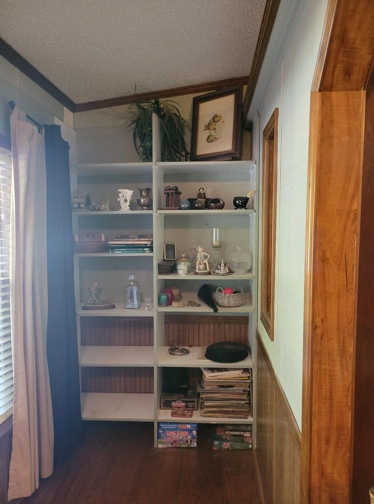 White bookshelf against a blue wall filled with decorative items, plants, and games.