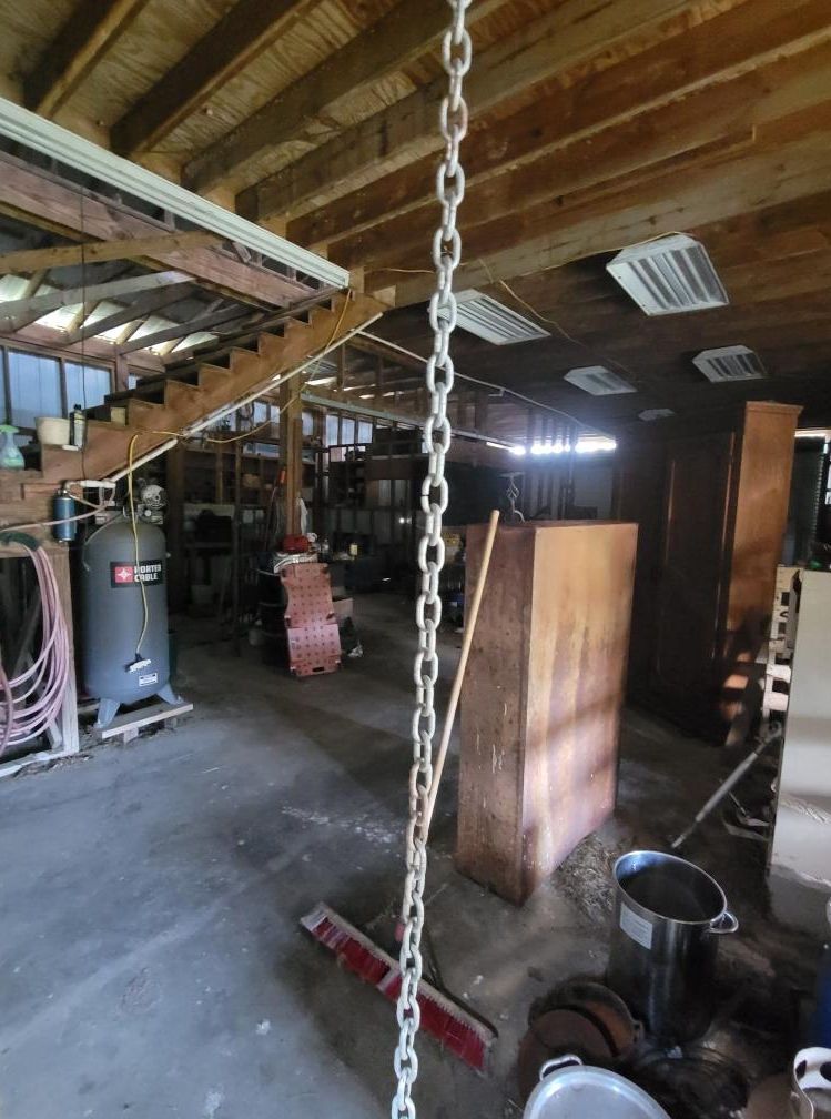 Workshop interior with chain hanging down, wood cabinets, air compressor, and stairs.