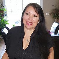 Woman with long dark hair smiles, wearing a black top. Inside a well-lit room. Woman with long dark hair smiles, wearing a black top. Inside a well-lit room.