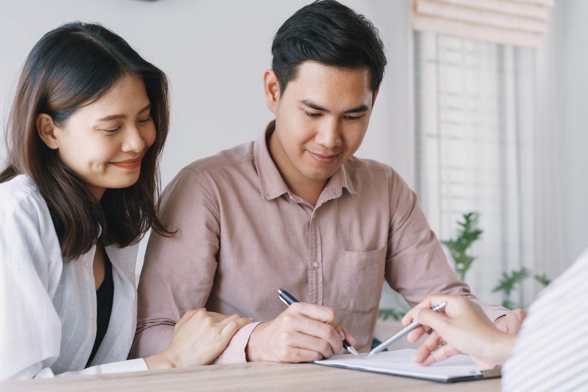 Couple signing documents with an advisor at a desk. Couple signing documents with an advisor at a desk.