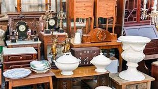 A collection of antique furniture and decorative items displayed at an outdoor flea market.
