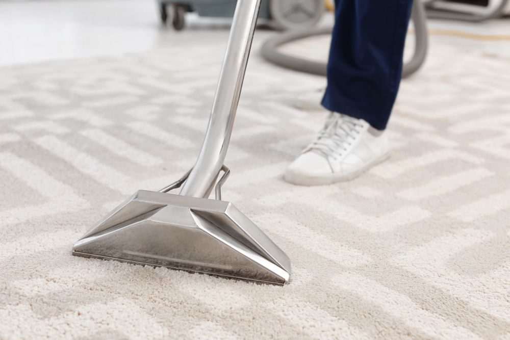 A Person Vacuuming a White Patterned Carpet with A Cleaning Machine — Port O' Call Cleaning In Airlie Beach, QLD