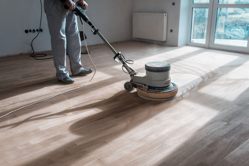 Person Sanding a Hardwood Floor With a Floor Buffer in a Room With a Window — Port O' Call Cleaning In Airlie Beach, QLD