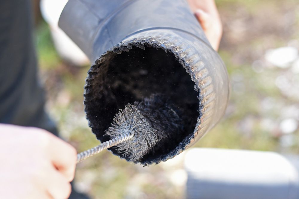 Person Cleaning a Black Exhaust Pipe With a Brush — Port O' Call Cleaning In Cannon Valley, QLD