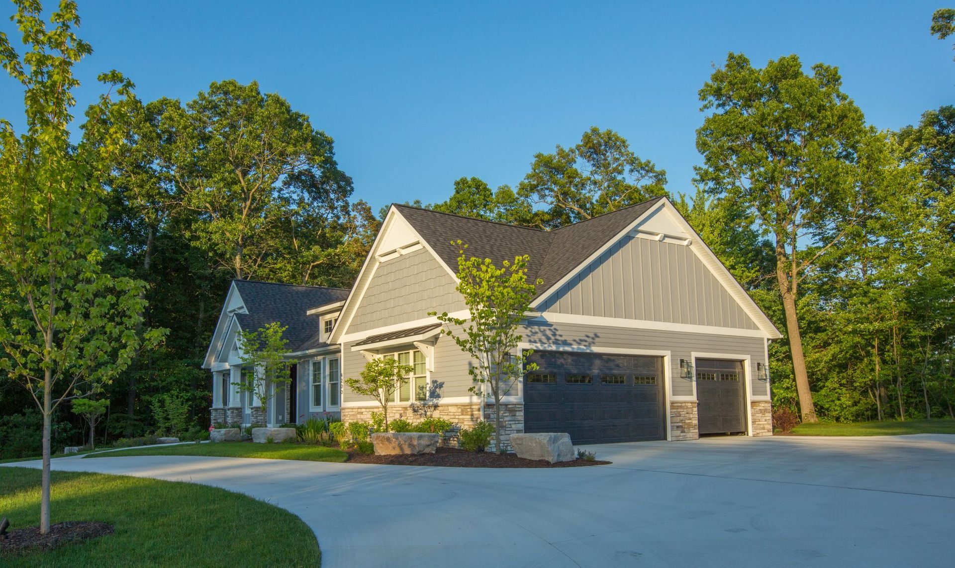 A large house with two garages and a driveway surrounded by trees.