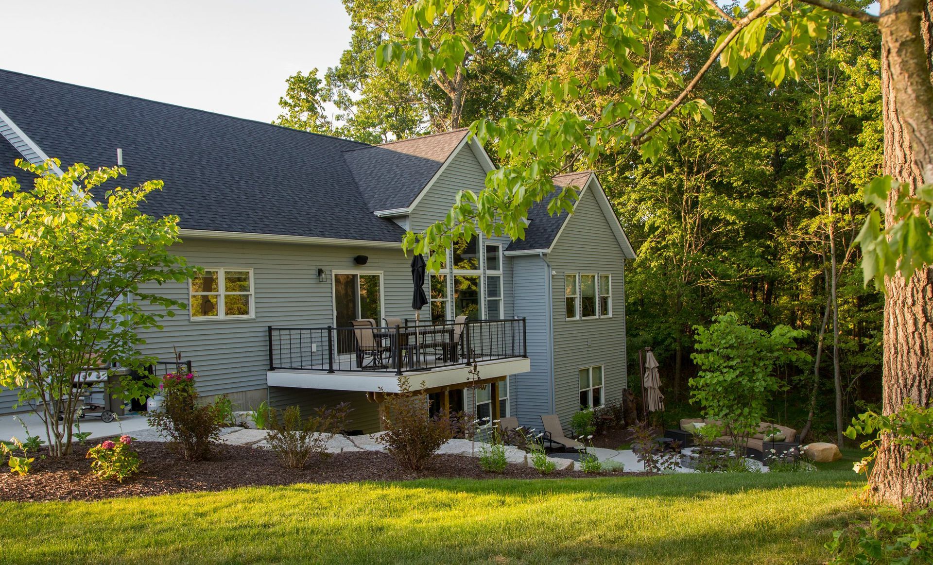 A large house with a large deck in the backyard surrounded by trees.