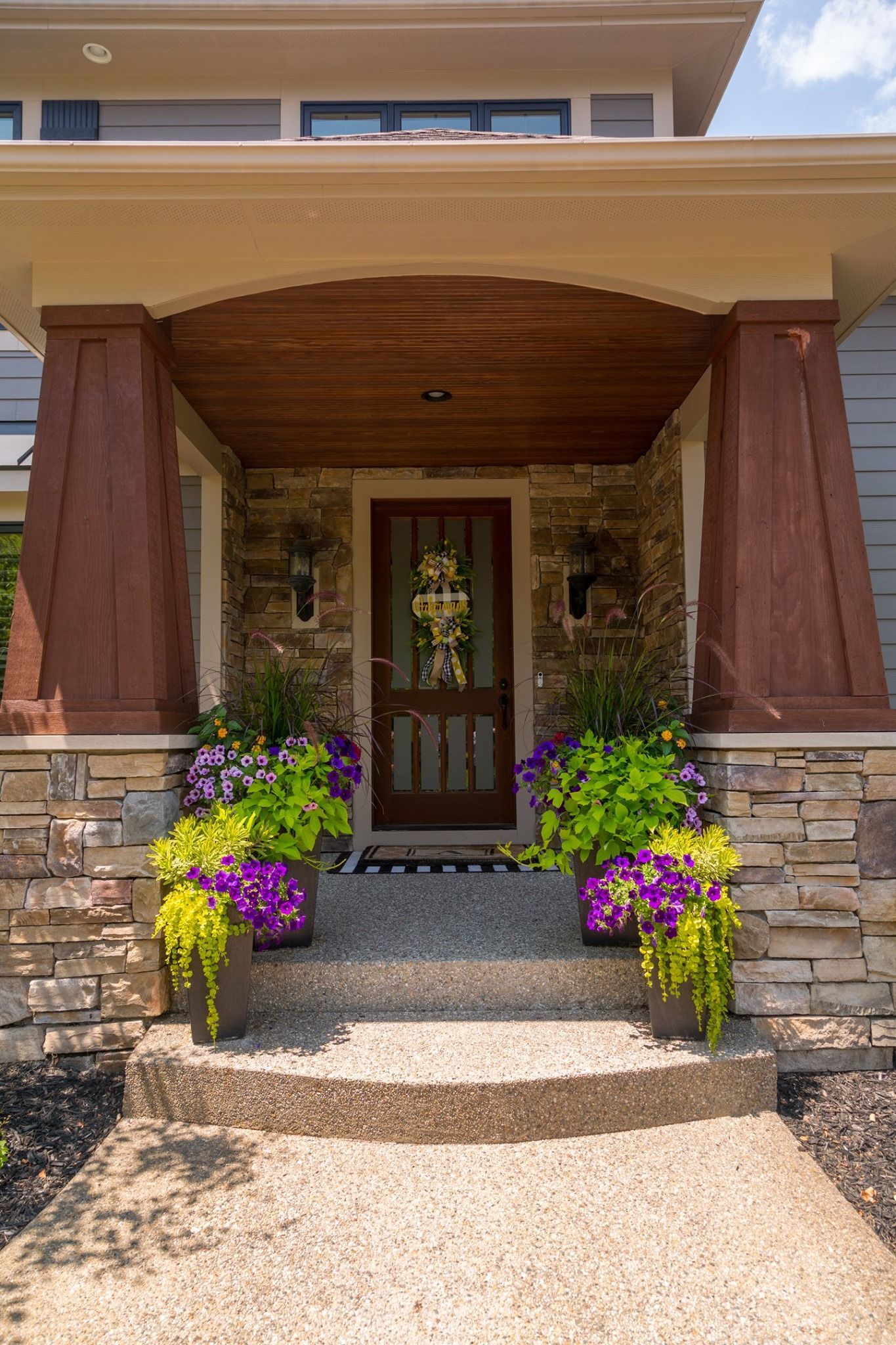 The front porch of a house is decorated with flowers and plants.