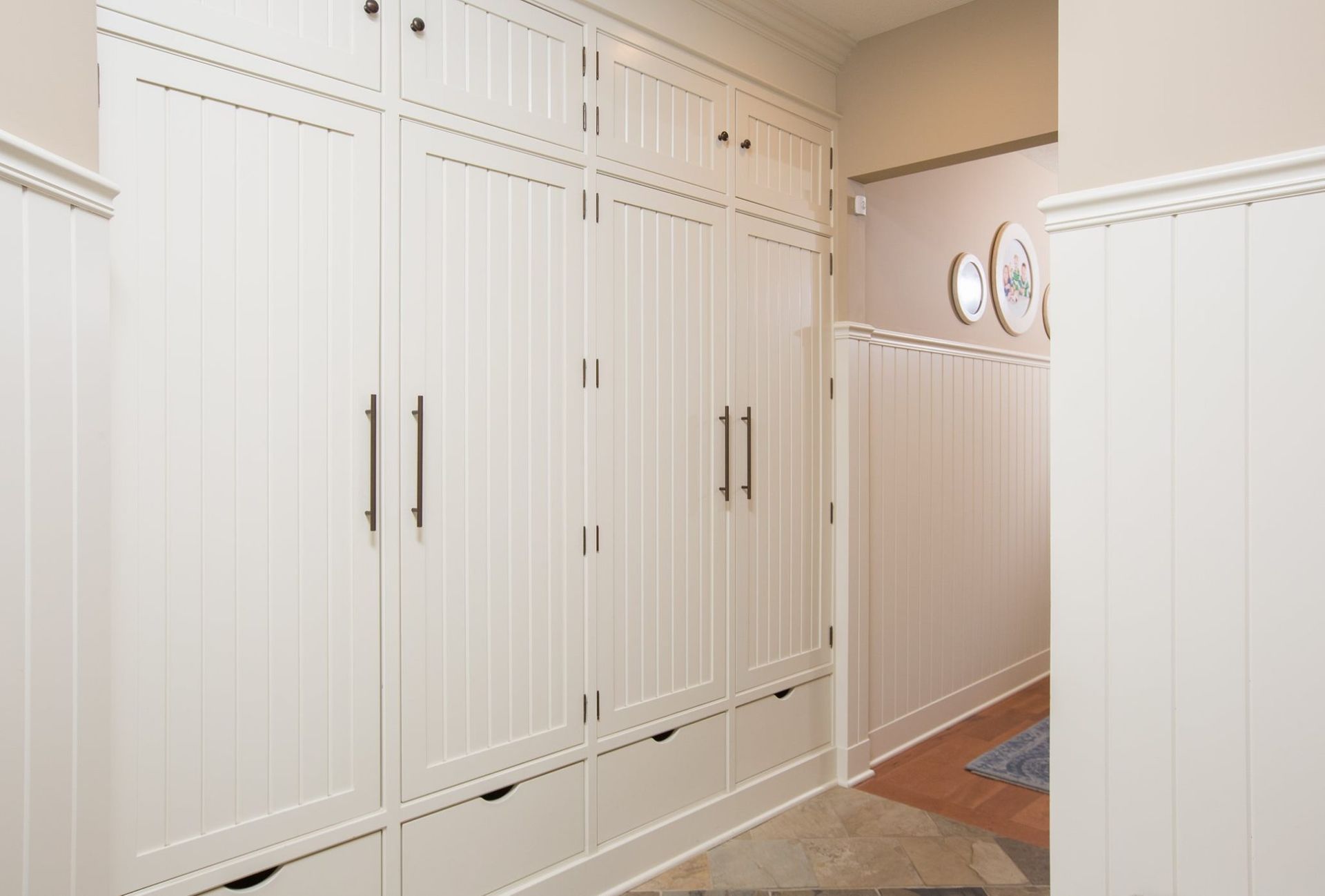 A hallway with a lot of white cabinets and drawers.