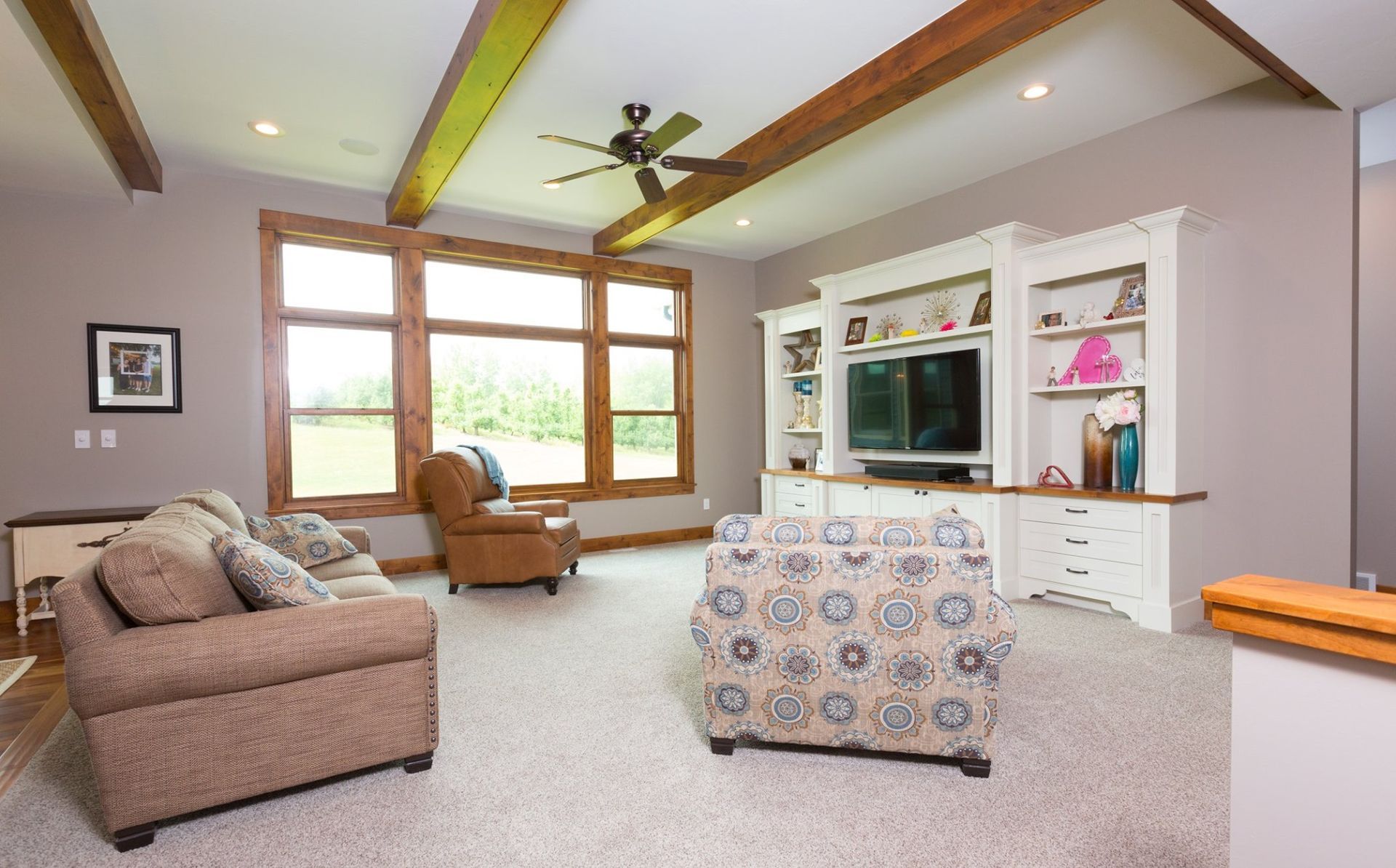 A living room with a couch , chair , television and ceiling fan.
