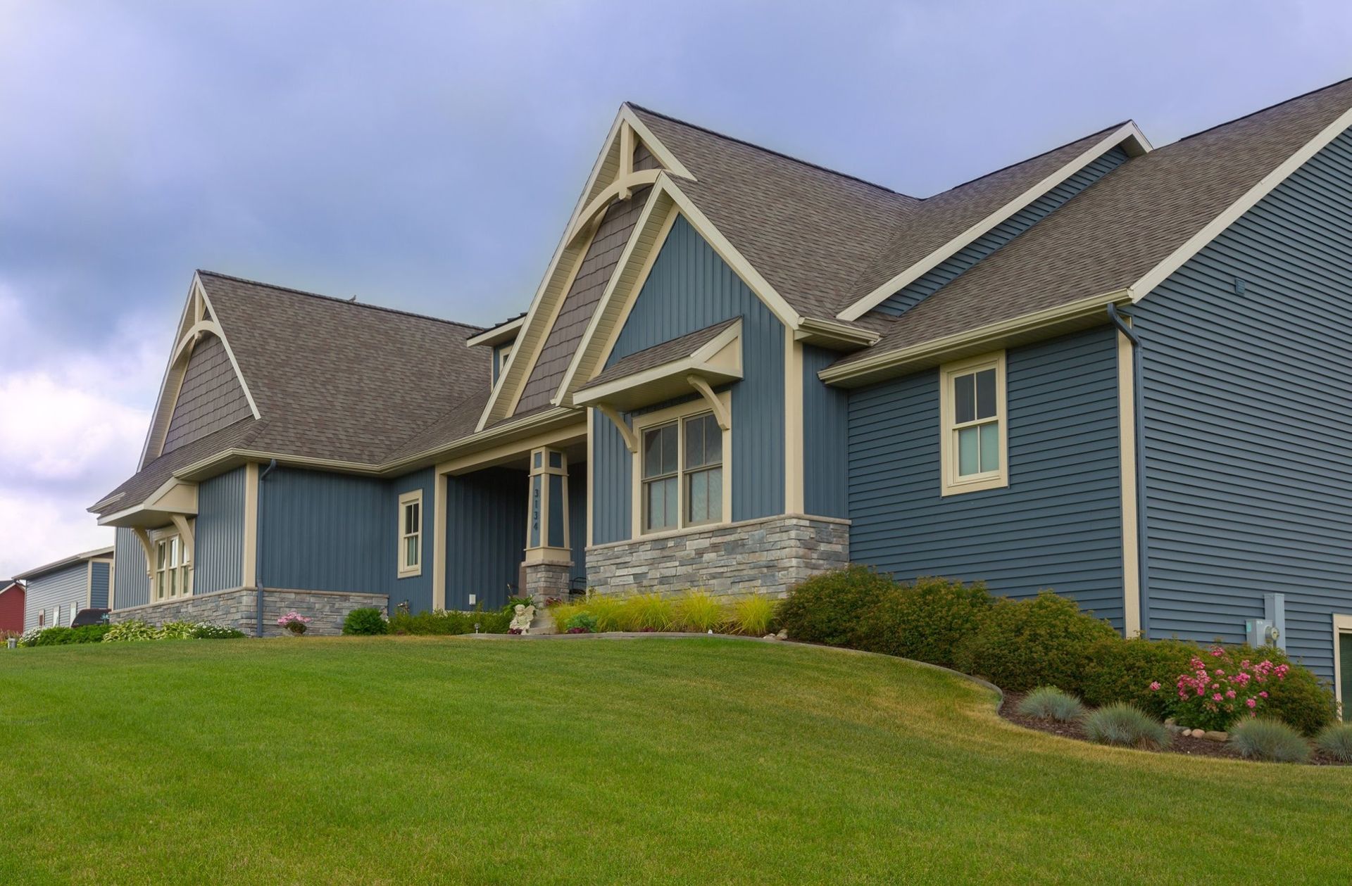 A large blue house sits on top of a lush green hillside