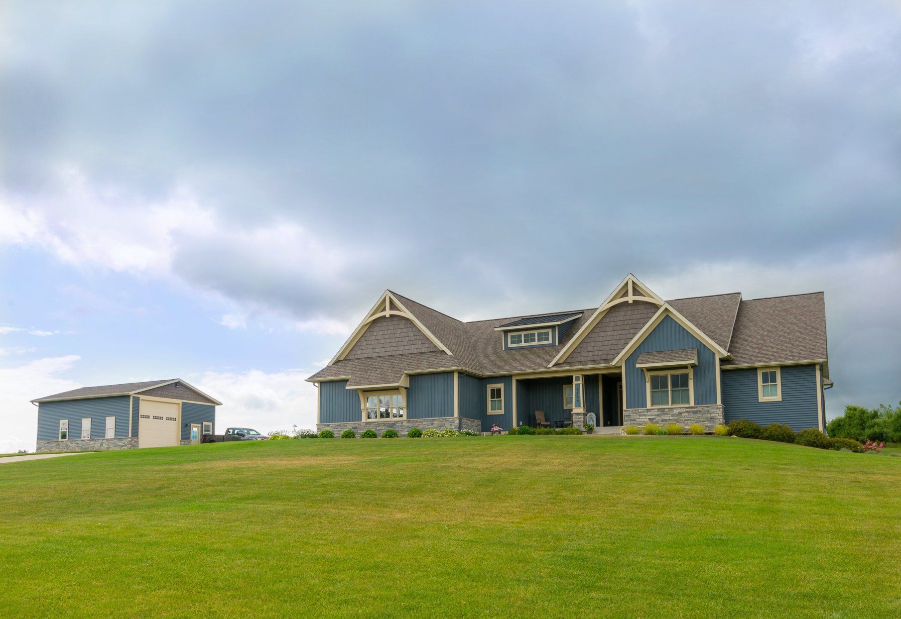 A large blue house is sitting on top of a lush green hill.