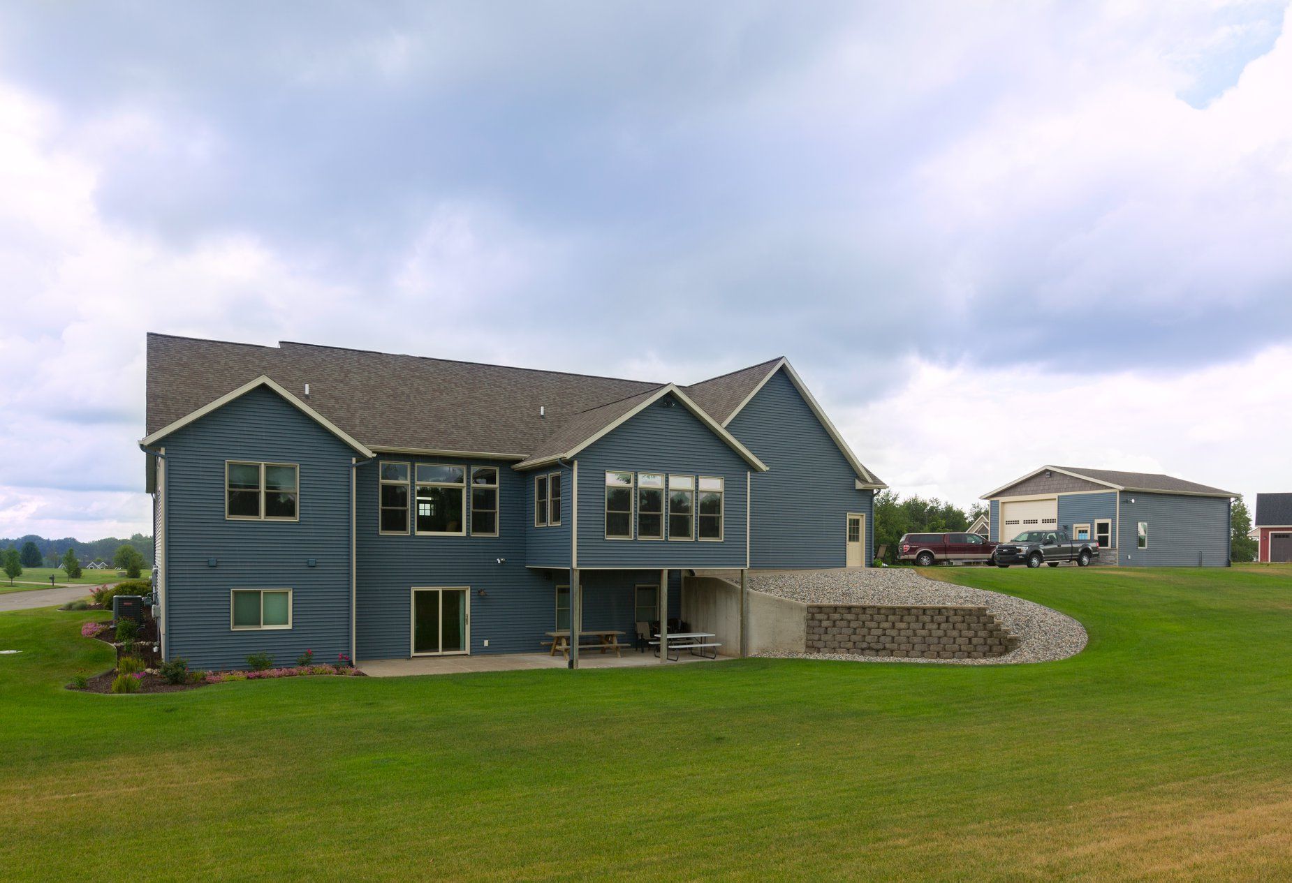 A large blue house sits in the middle of a lush green field